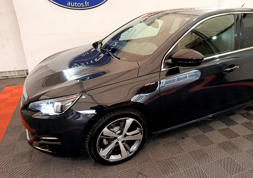 Vue 3/4 avant droit d'une Peugeot 308 gris foncé avec phares LED et jantes alliage distinctives.