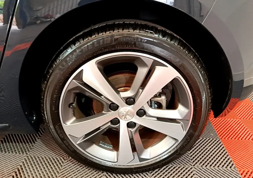Gros plan sur la roue avant gauche du Peugeot 308 gris foncé, mettant en valeur la jante alliage et le pneu Michelin.