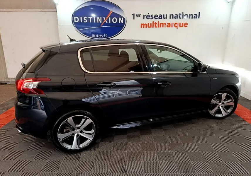 Peugeot 308 gris foncé vue de profil côté gauche, avec jantes alliage et feux arrière LED en intérieur showroom.