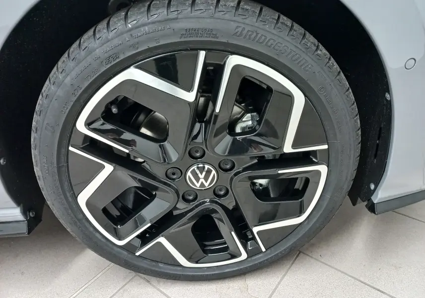 Gros plan sur la roue avant droite avec jante noire et argentée de la Volkswagen Golf 2.0 TDI Gris Lunaire 2026.