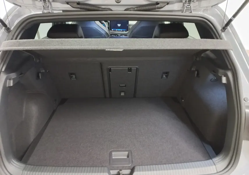 Coffre ouvert vu de l'arrière d'une Volkswagen Golf gris lunaire avec banquette arrière et tablette cache-bagages.