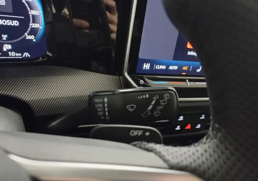 Gros plan intérieur sur la commande d’essuie-glace à gauche du volant d’une Volkswagen Golf gris lunaire, avec tableau de bord numérique en arrière-plan.