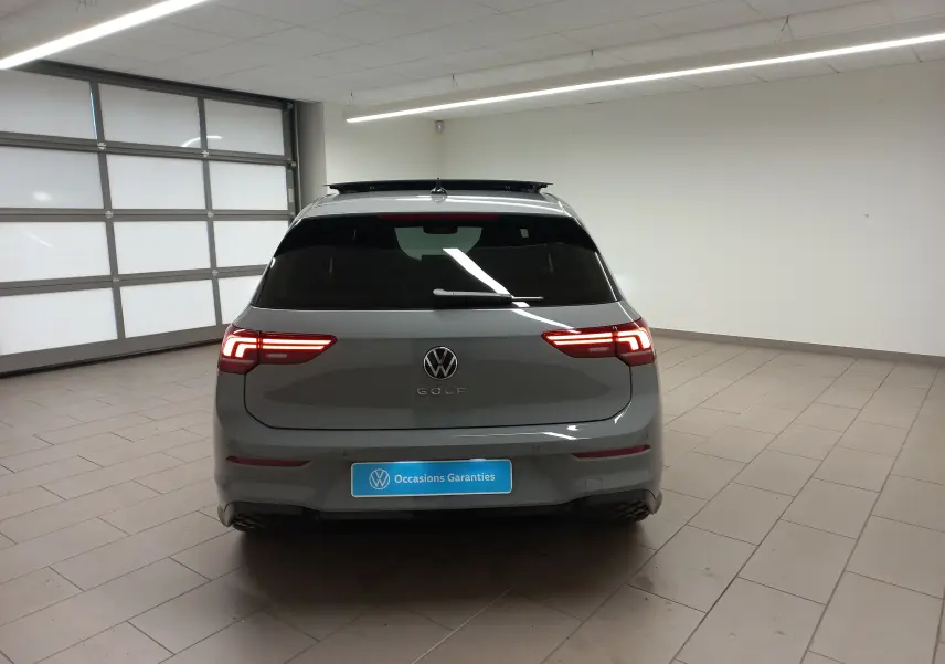 Vue arrière d'une Volkswagen Golf 2.0 TDI R-Line gris lunaire avec toit ouvrant panoramique en intérieur showroom.