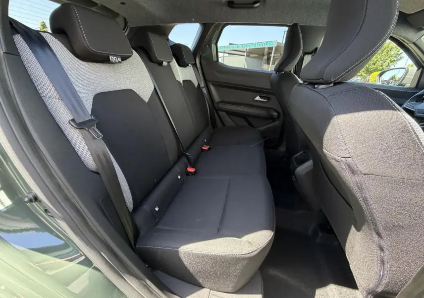 Vue latérale gauche de l'habitacle arrière du Dacia Duster III hybride en kaki lichen, montrant les sièges tissu bicolores.