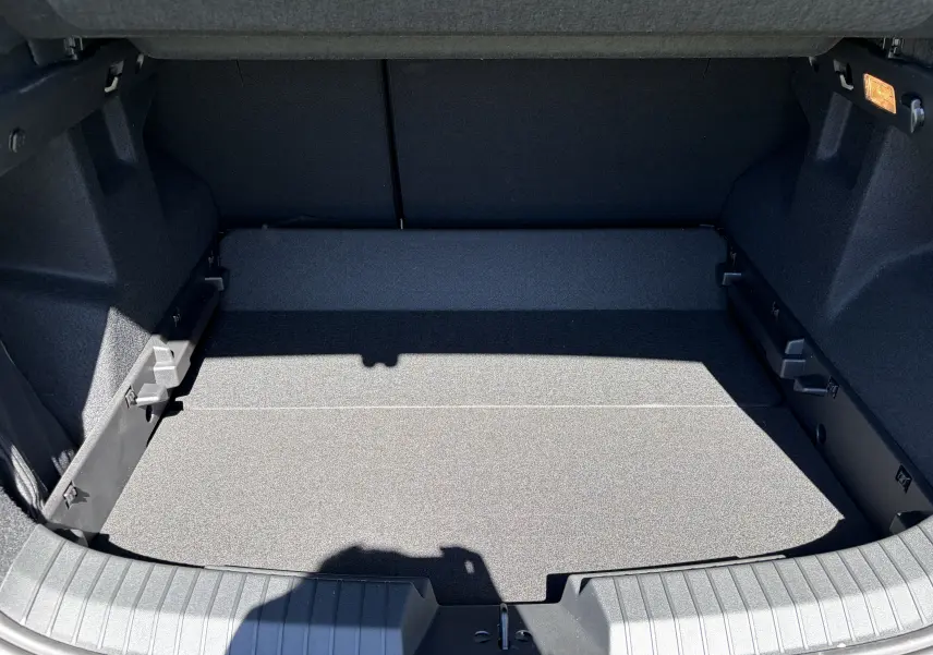 Coffre ouvert vu de l'arrière d'un Dacia Duster III hybride, espace de chargement vide et revêtement gris.