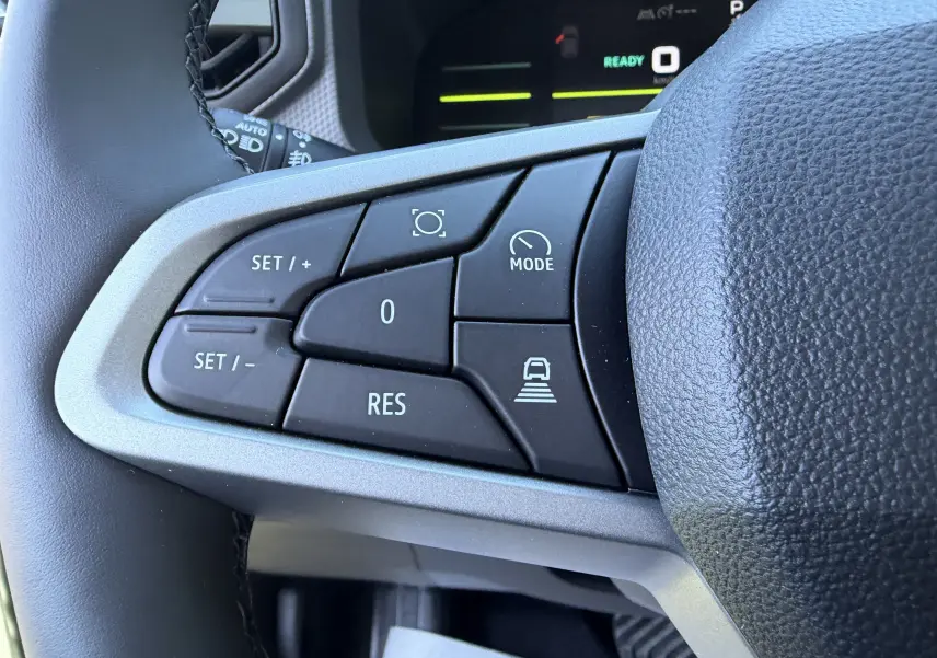 Gros plan sur les boutons de commande au volant côté gauche du Dacia Duster III hybride, finition noire et grise.