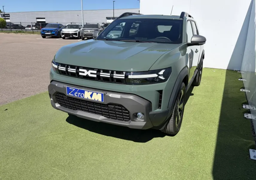 Vue 3/4 avant droit d'un Dacia Duster III hybride 2026 en kaki lichen avec calandre noire et jantes alliage 18 pouces.