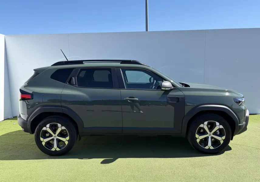 Vue de profil côté gauche d'un Dacia Duster III 2026 en kaki lichen avec jantes alliage 18 pouces diamantées.