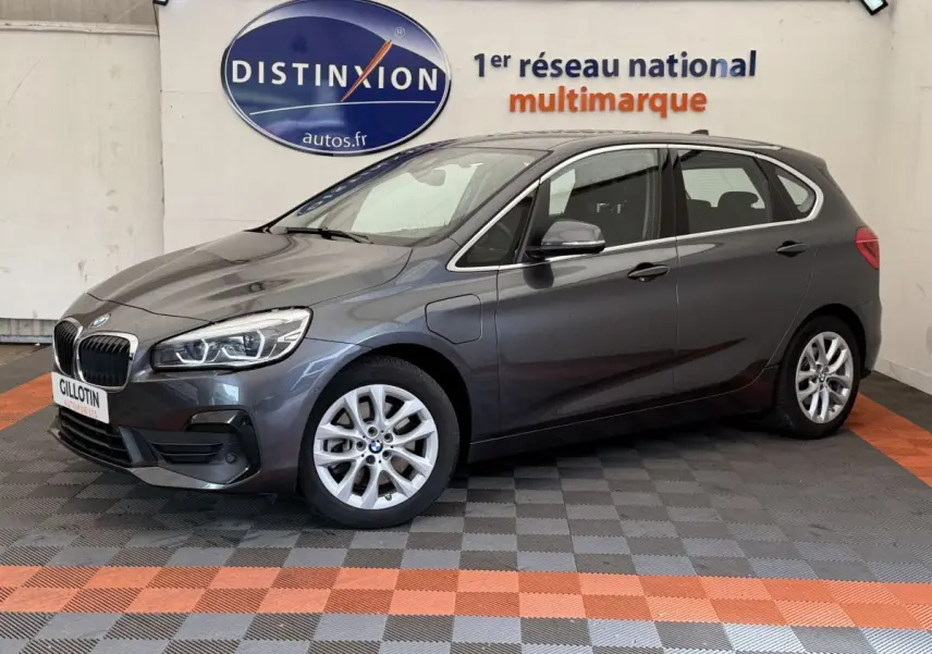 BMW Série 2 Active Tourer gris foncé vue 3/4 avant côté gauche dans un showroom multimarque.