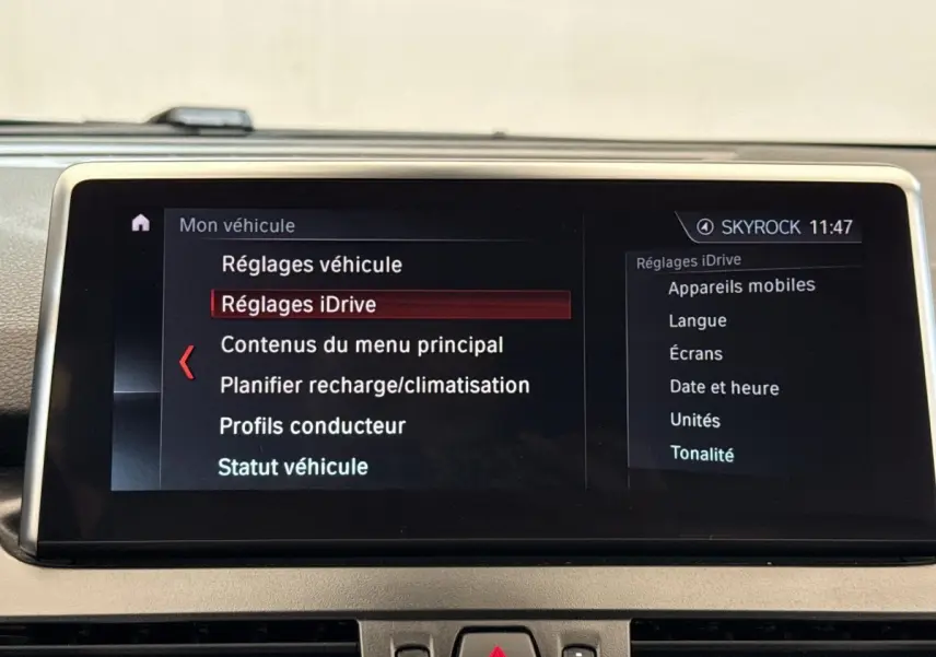 Écran tactile central affichant le menu iDrive de la BMW Série 2 Active Tourer 225xe gris foncé, vue intérieure frontale.