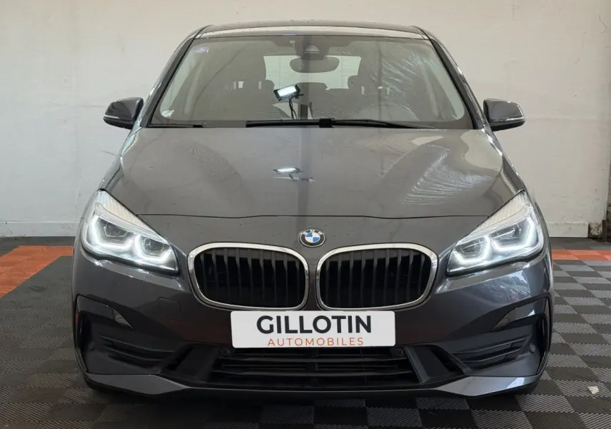 Vue frontale d'une BMW Série 2 Active Tourer gris foncé avec phares LED allumés et calandre double haricot.