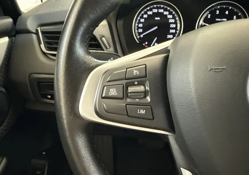 Gros plan sur le volant cuir noir de la BMW Série 2 Active Tourer 225xe avec commandes de régulateur de vitesse.