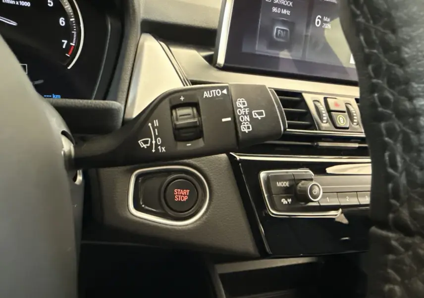 Détail intérieur côté gauche du tableau de bord gris foncé avec bouton Start/Stop et commandes essuie-glaces BMW Série 2 Active Tourer.