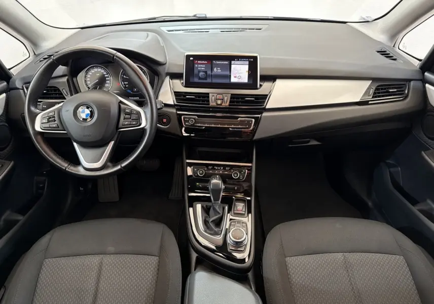 Vue intérieure avant de la BMW Série 2 Active Tourer 225xe, tableau de bord noir avec écran tactile central et volant cuir.