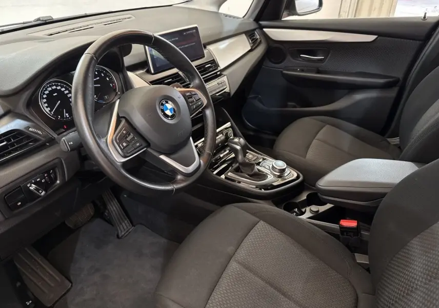 Vue intérieure côté conducteur de la BMW Série 2 Active Tourer 225xe gris foncé, avec volant cuir multifonctions et écran tactile central.