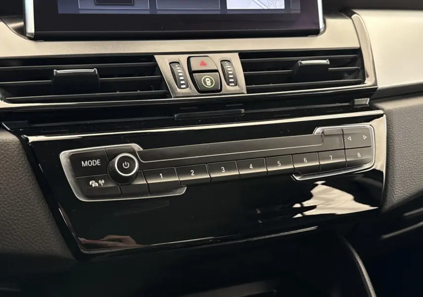 Détail du tableau de bord noir brillant de la BMW Série 2 Active Tourer 225xe avec commandes multimédia et ventilation.