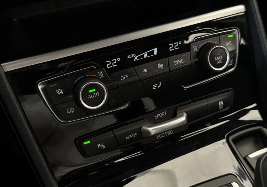 Détail du panneau de commande de la climatisation bi-zone et modes de conduite sur BMW Série 2 Active Tourer gris foncé.