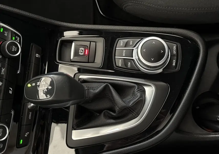Gros plan sur la console centrale noire brillante de la BMW Série 2 Active Tourer 225xe avec levier de vitesse automatique et molette de contrôle.