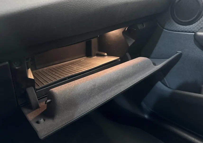 Gros plan sur la boîte à gants ouverte côté passager de la BMW Série 2 Active Tourer 225xe gris foncé, intérieur sombre.
