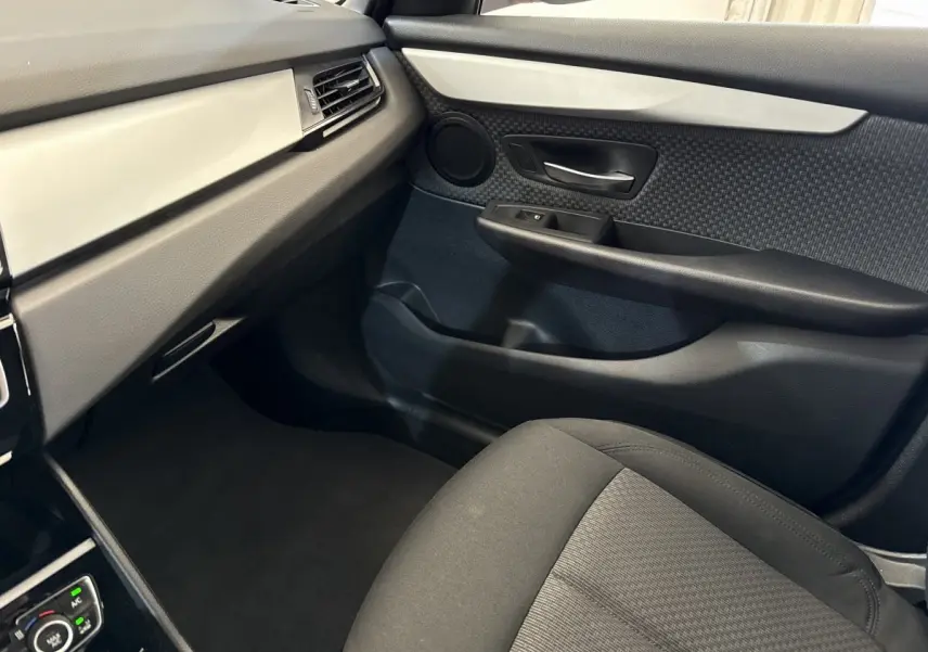 Vue intérieure côté passager avant de la BMW Série 2 Active Tourer 225xe, avec sellerie noire et panneau de porte texturé.