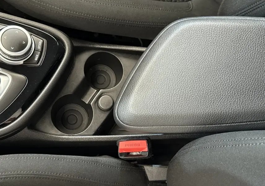 Gros plan intérieur sur la console centrale noire et les porte-gobelets de la BMW Série 2 Active Tourer 225xe gris foncé.