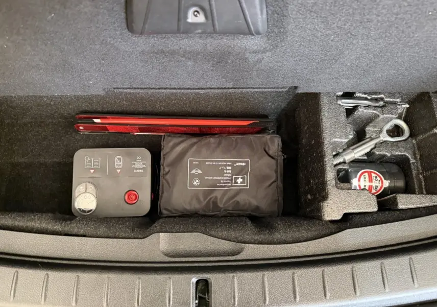 Vue plongeante sur le compartiment de rangement sous coffre d'une BMW Série 2 Active Tourer gris foncé avec kit de secours et outils.