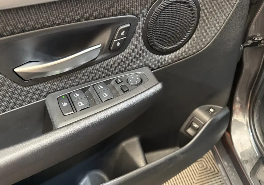 Détail de la porte avant gauche gris foncé d’une BMW Série 2 Active Tourer avec commandes électriques et haut-parleur intégré.
