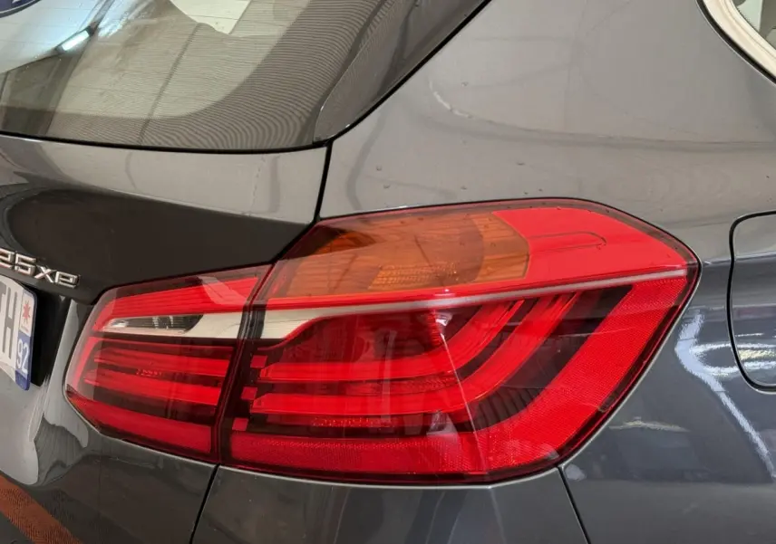 Gros plan sur le feu arrière droit rouge et orange d'une BMW Série 2 Active Tourer gris foncé, version 225xe.