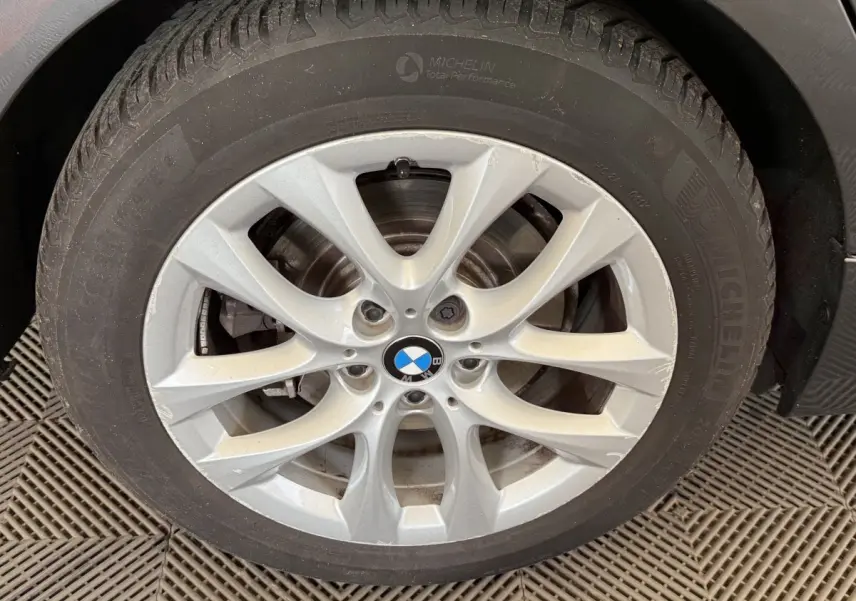 Gros plan sur la roue avant droite avec jante argentée BMW et pneu Michelin sur BMW Série 2 Active Tourer gris foncé.