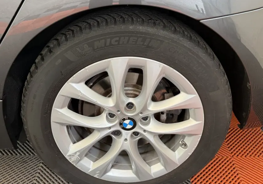 Gros plan sur la roue arrière droite d’une BMW Série 2 Active Tourer 225xe gris foncé, avec passage de roue et partie de carrosserie visible.