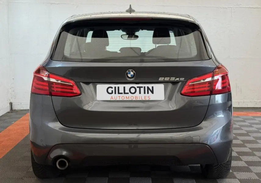 Vue arrière d'une BMW Série 2 Active Tourer 225xe gris foncé avec feux rouges et logo visible sur fond neutre.