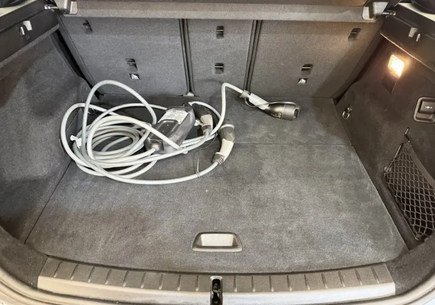 Coffre ouvert vu de face d’une BMW Série 2 Active Tourer gris foncé avec câble de recharge hybride posé au sol.