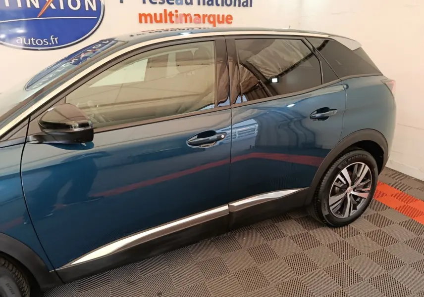 Profil côté gauche du Peugeot 3008 bleu 2022 avec jantes alliage et toit noir contrasté visible en intérieur showroom.