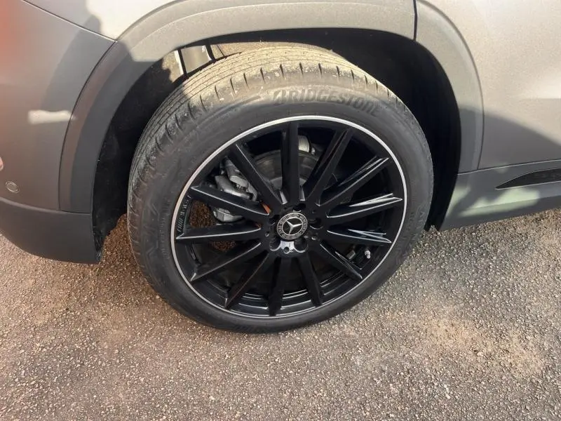 Gros plan sur la roue avant droite noire à jantes alu du Mercedes GLA 200 d gris montagne magno MANUFAKTUR.