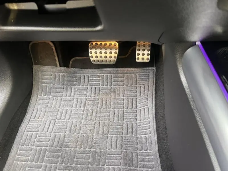 Vue rapprochée des pédales sport en métal brossé et du tapis de sol gris dans une Mercedes GLA 200 d AMG Line 2021.