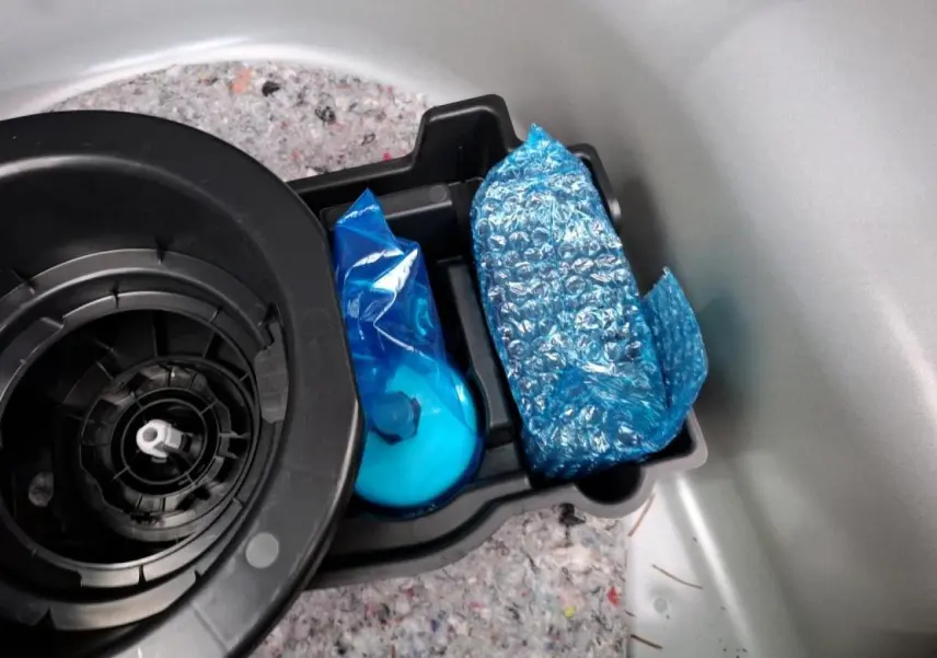 Détail du compartiment de rangement dans le coffre d’une Opel Corsa gris clair, avec kit anti-crevaison emballé.