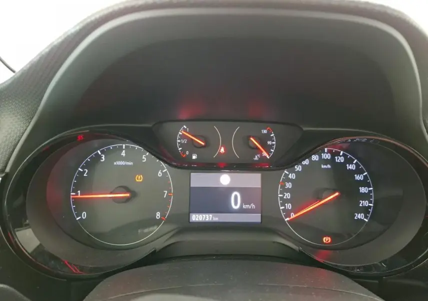 Vue rapprochée du tableau de bord digital de l'Opel Corsa gris clair, affichant 0 km/h et 20 737 km au compteur.