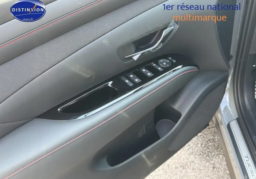 Gros plan sur la porte avant gauche gris shadow du Hyundai Tucson 2026 avec commandes de vitres et poignée intérieure.