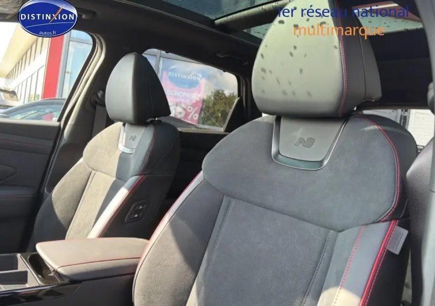 Gros plan sur les sièges avant gris alcantara avec surpiqûres rouges du Hyundai Tucson N Line 2026, intérieur lumineux.