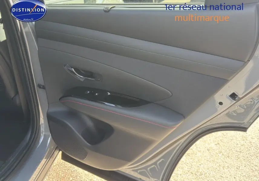 Vue rapprochée de la porte arrière gauche grise shadow du Hyundai Tucson avec garniture noire et surpiqûres rouges.