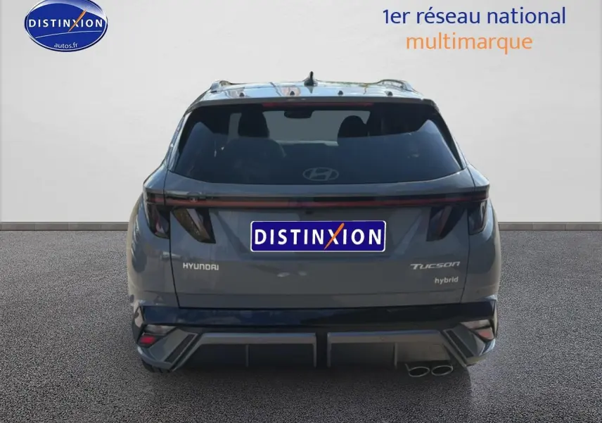 Vue arrière d’un Hyundai Tucson gris shadow hybride 2026 avec feux LED et double sortie d’échappement visible à droite.
