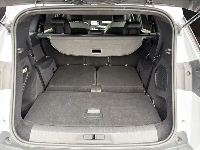 Coffre ouvert du Peugeot 5008 blanc Okenite, vue arrière montrant banquette rabattue et cache-bagages déployé.