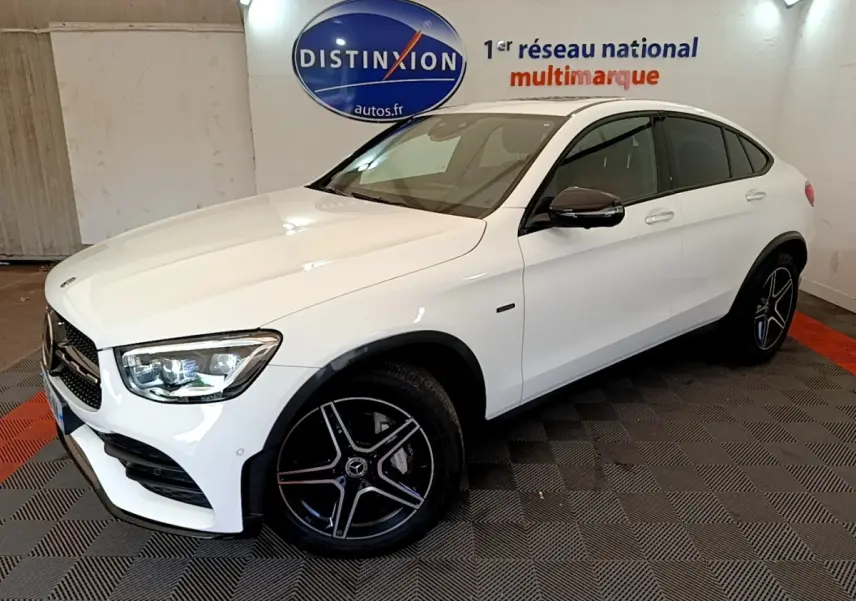 Vue 3/4 avant droit d'un Mercedes GLC Coupé blanc avec jantes AMG noires et vitres teintées.