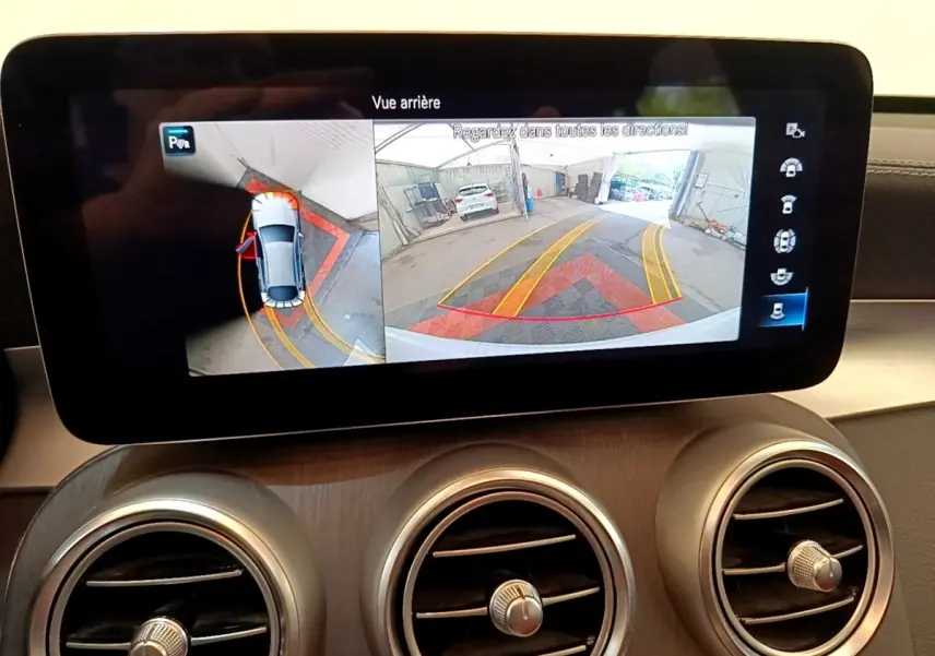 Écran central affichant la caméra de recul et vue 360° d’un Mercedes GLC Coupé blanc en intérieur.