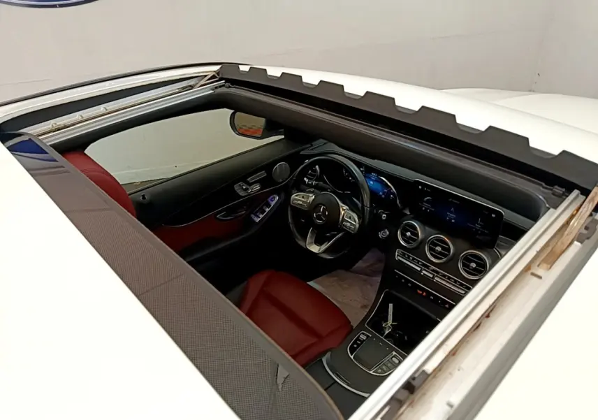 Vue plongeante sur l’intérieur rouge et noir d’un Mercedes GLC Coupé blanc, avec toit ouvrant panoramique ouvert.