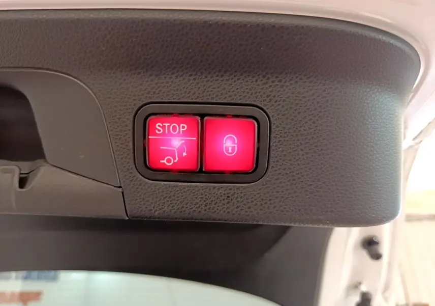 Gros plan sur les boutons rouges d'ouverture et de verrouillage électrique du coffre d'un Mercedes GLC Coupé blanc.