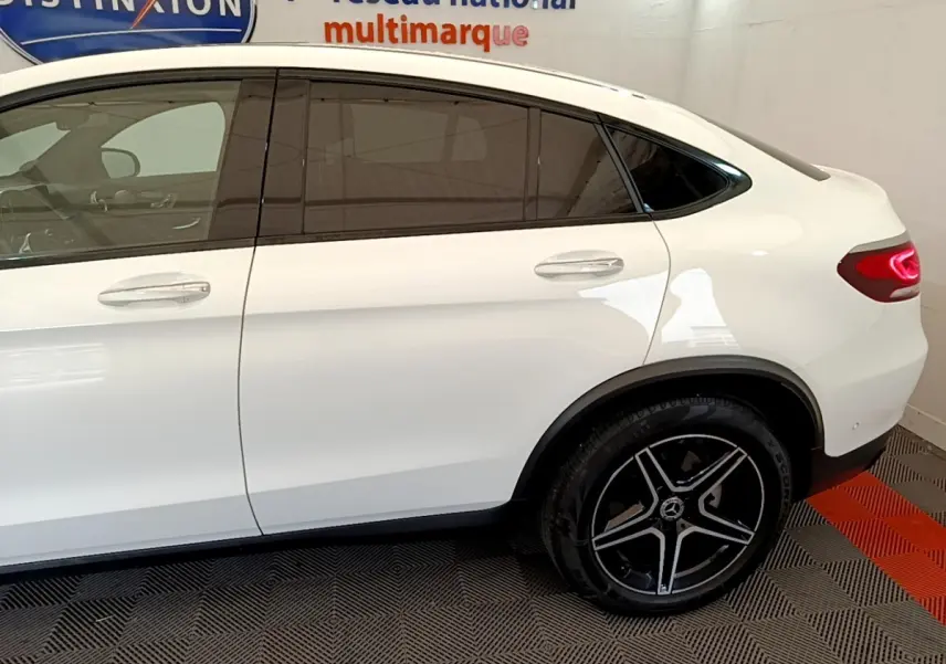 Vue latérale droite d'un Mercedes GLC Coupé blanc avec jantes AMG noires et vitres teintées.