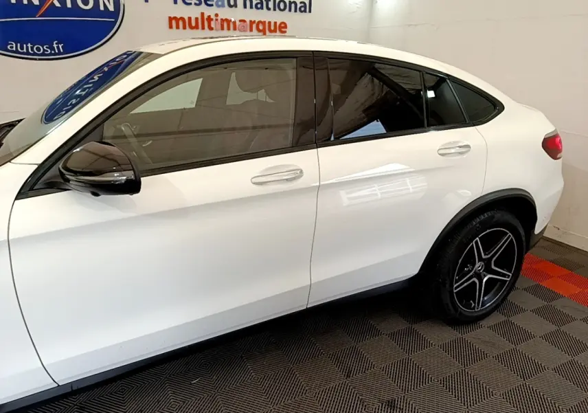Vue latérale droite d’un Mercedes GLC Coupé blanc avec jantes noires et rétroviseurs noirs brillants.