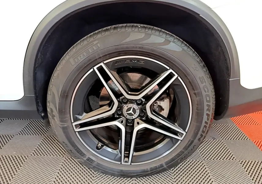 Gros plan sur la roue avant droite noire AMG avec jante étoile sur Mercedes GLC Coupé blanc.