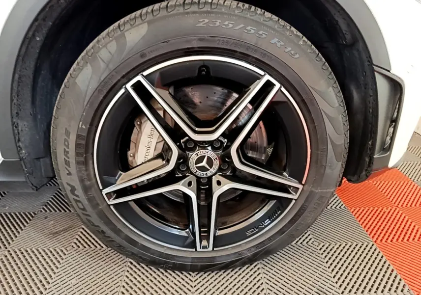 Gros plan sur la roue avant gauche du Mercedes GLC 300 e AMG Line blanc, jante alliage noir à cinq branches.